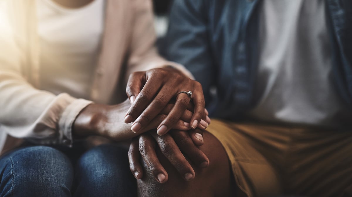 Cropped shot of a man and woman sitting on a sofa and holding hands
