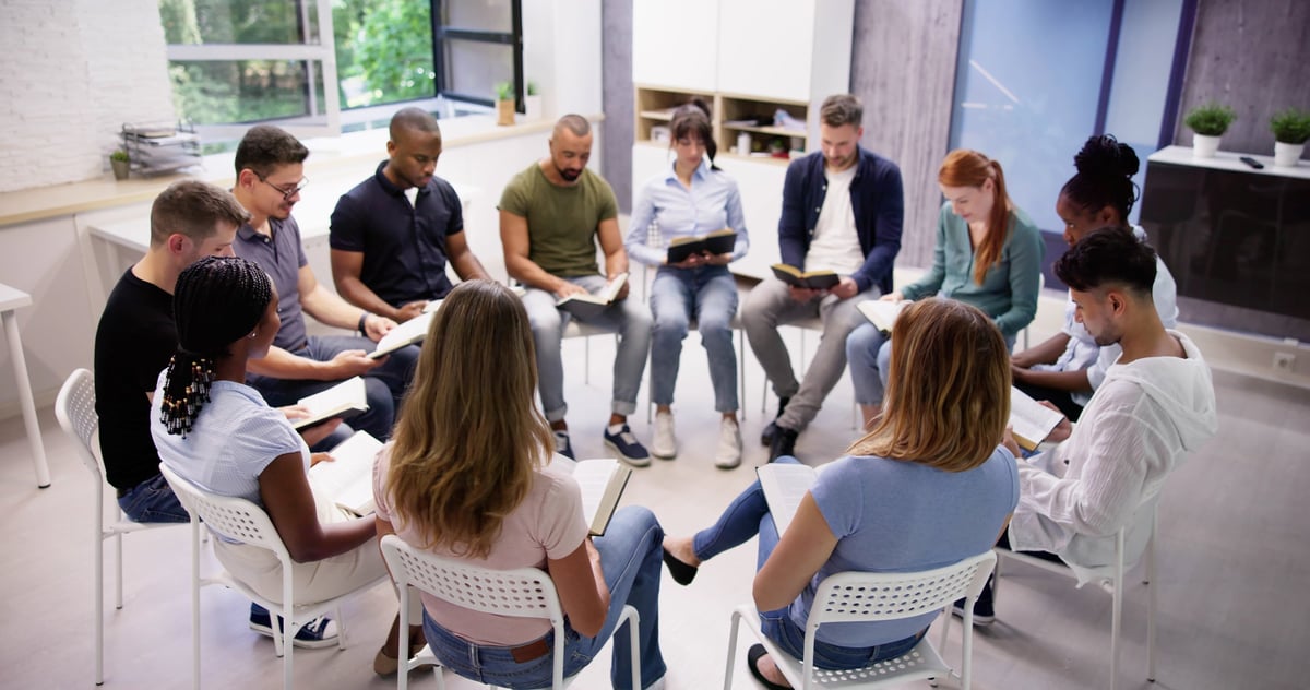 Diverse group reading and studying Bible together in circle