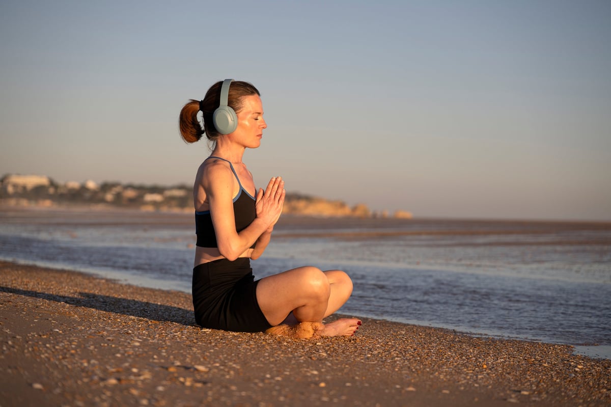 fit sporty woman sitting on the beach practicing yoga and meditation at sunrise, sunset